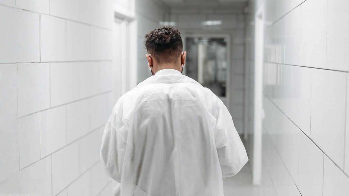 A young doctor walks down a hall between patients. He is practicing the cornerback mentality after the last patient visit didn't go as well as he would have liked.